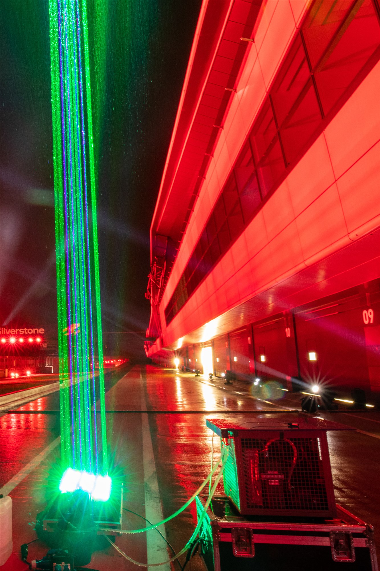 Green laser beams beside a red-lit Silverstone building