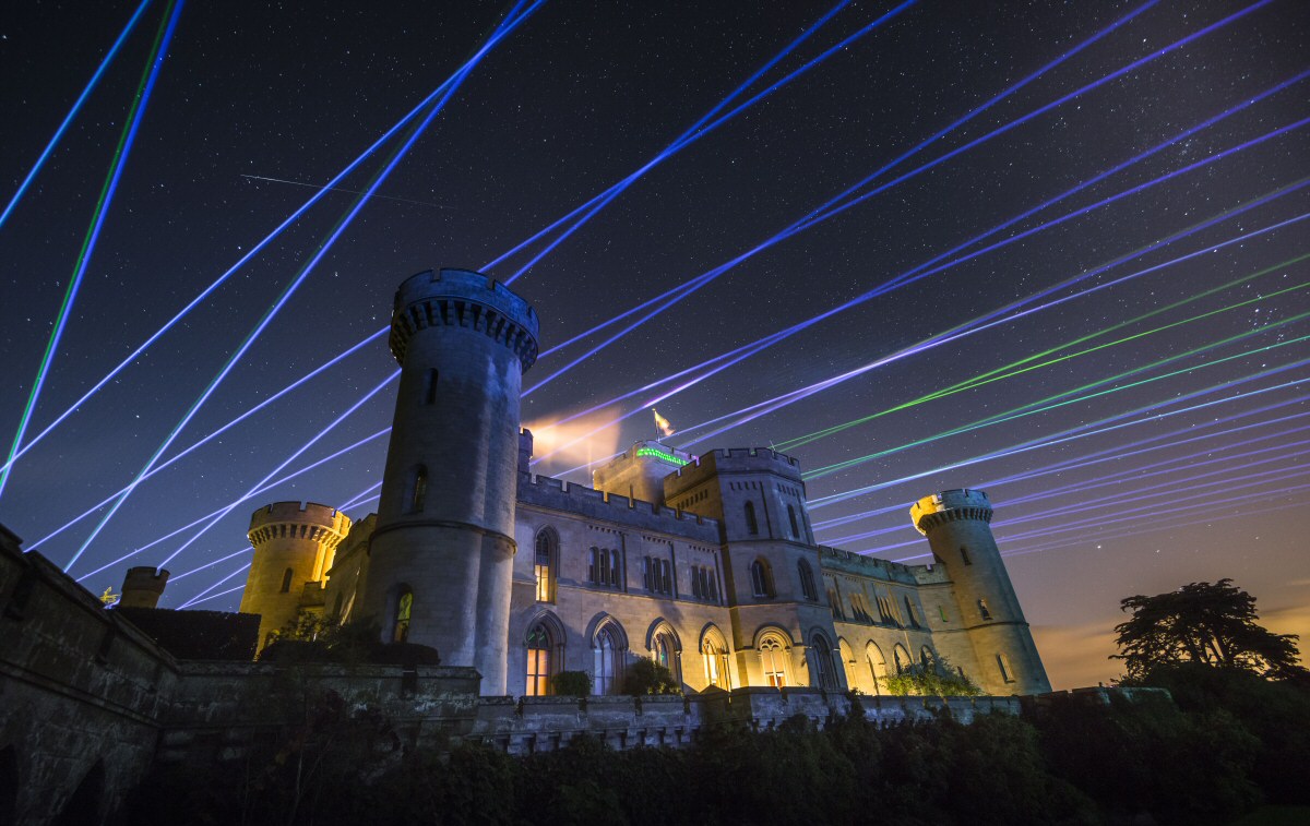Colourful laser beams illuminate the night sky above Eastnor Castle